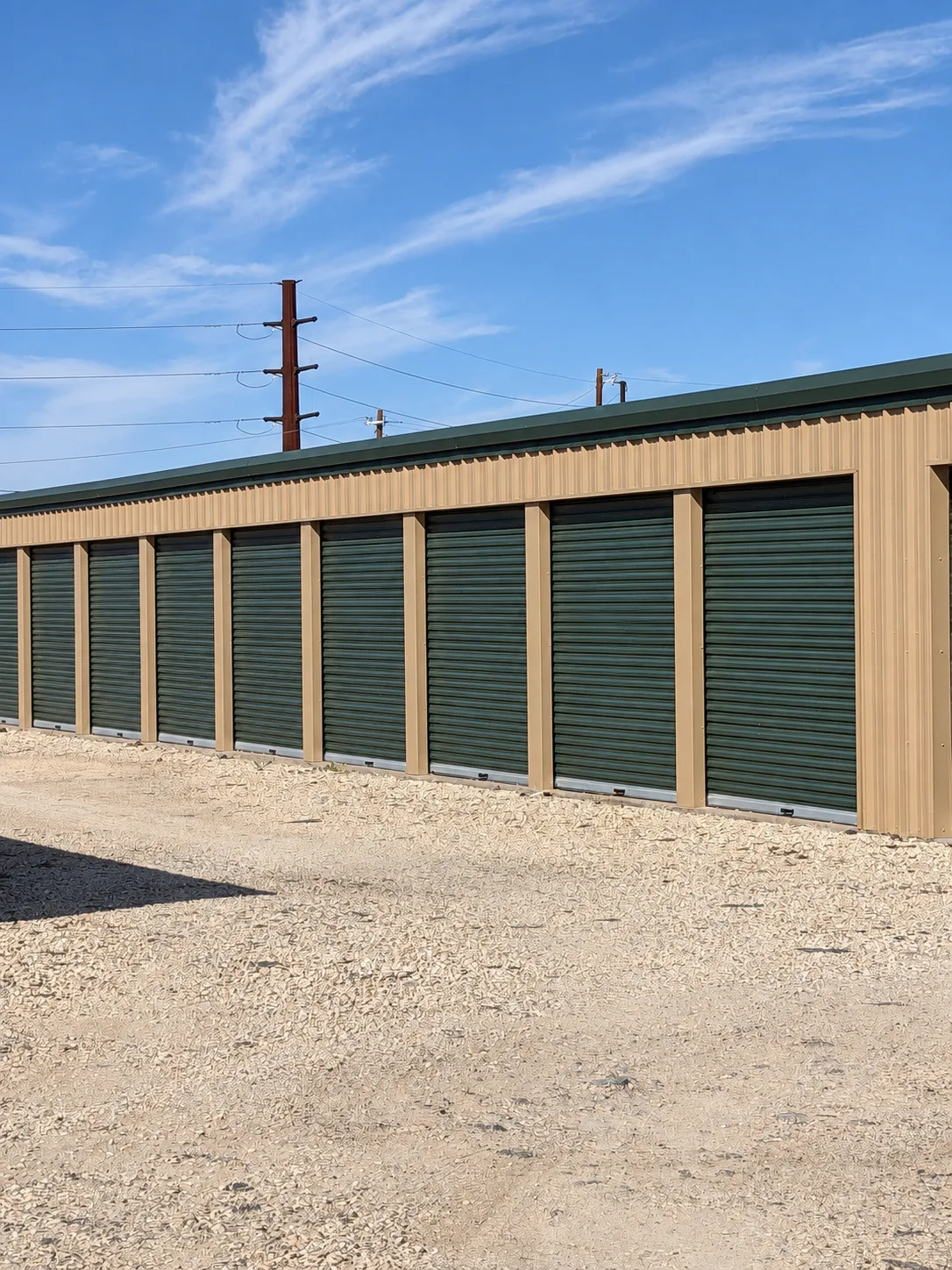 Close view of dark green roll-up storage doors and tan metal siding